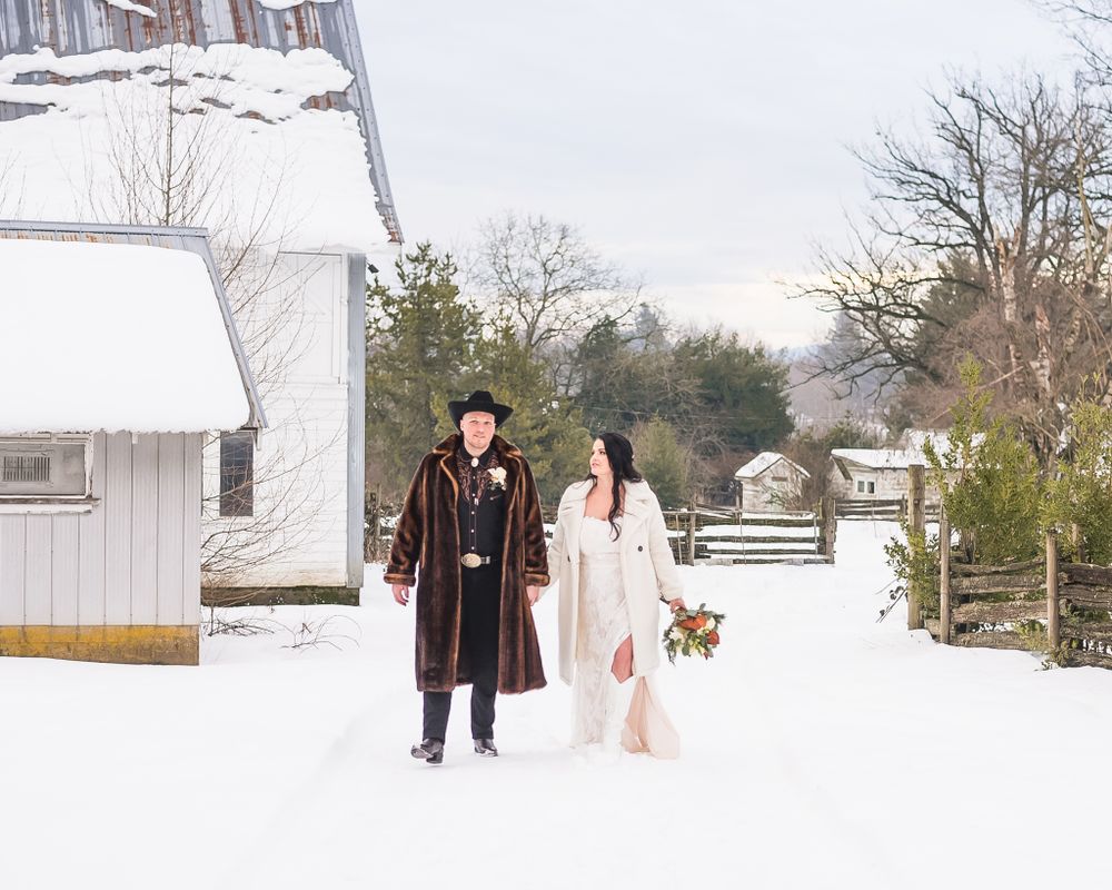 A couple walk hand in hand outside in the snow on their wedding day.