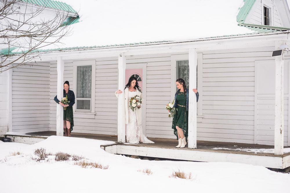 A wedding party poses on the porch of a house.