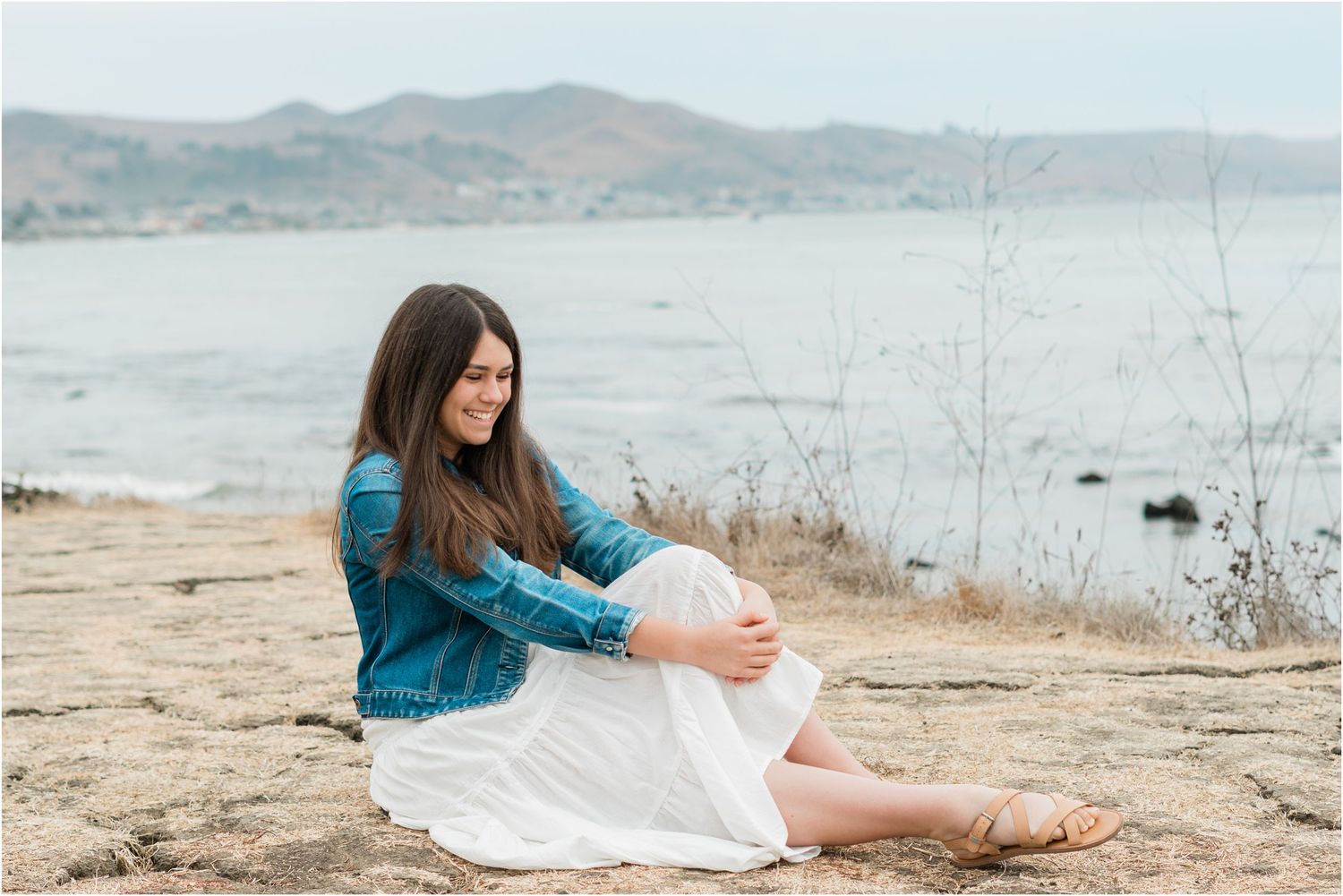 slo high senior photo shoot in white dress and jean jacket on the cliffs on Estero bluffs in cayucos for san luis obispo senior photos