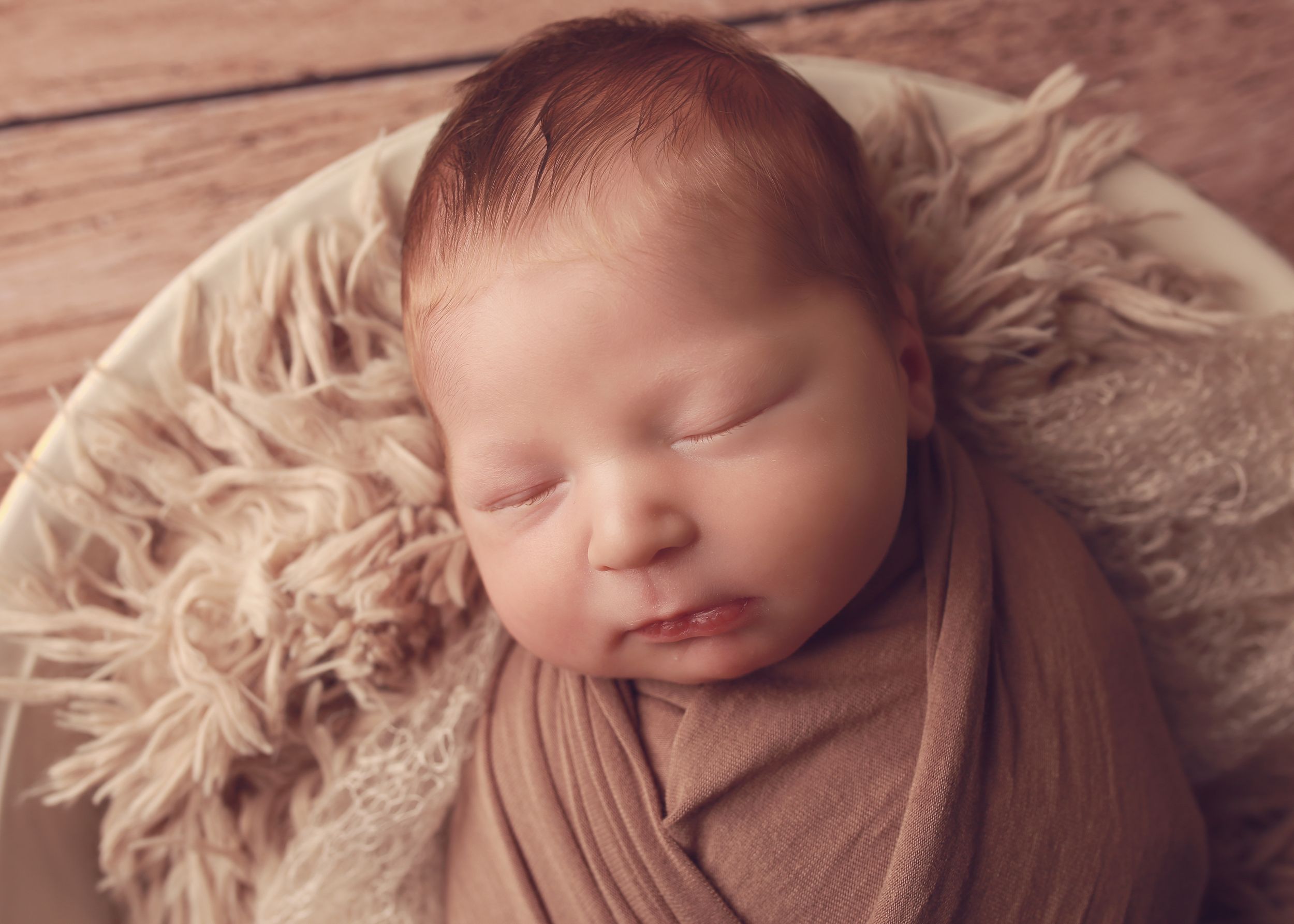A peaceful newborn baby boy wrapped in soft fabrics, captured in a serene and intimate setting, showcasing the delicate beauty of early life