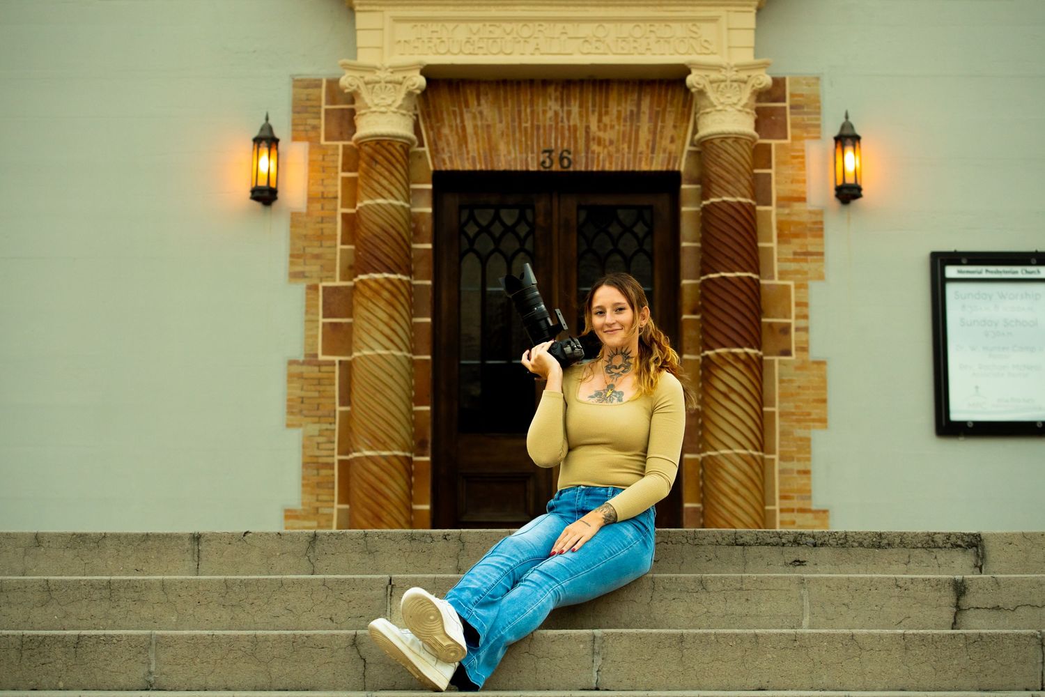 Someone sitting casually on stone steps near an ornate doorway with wall lanterns.