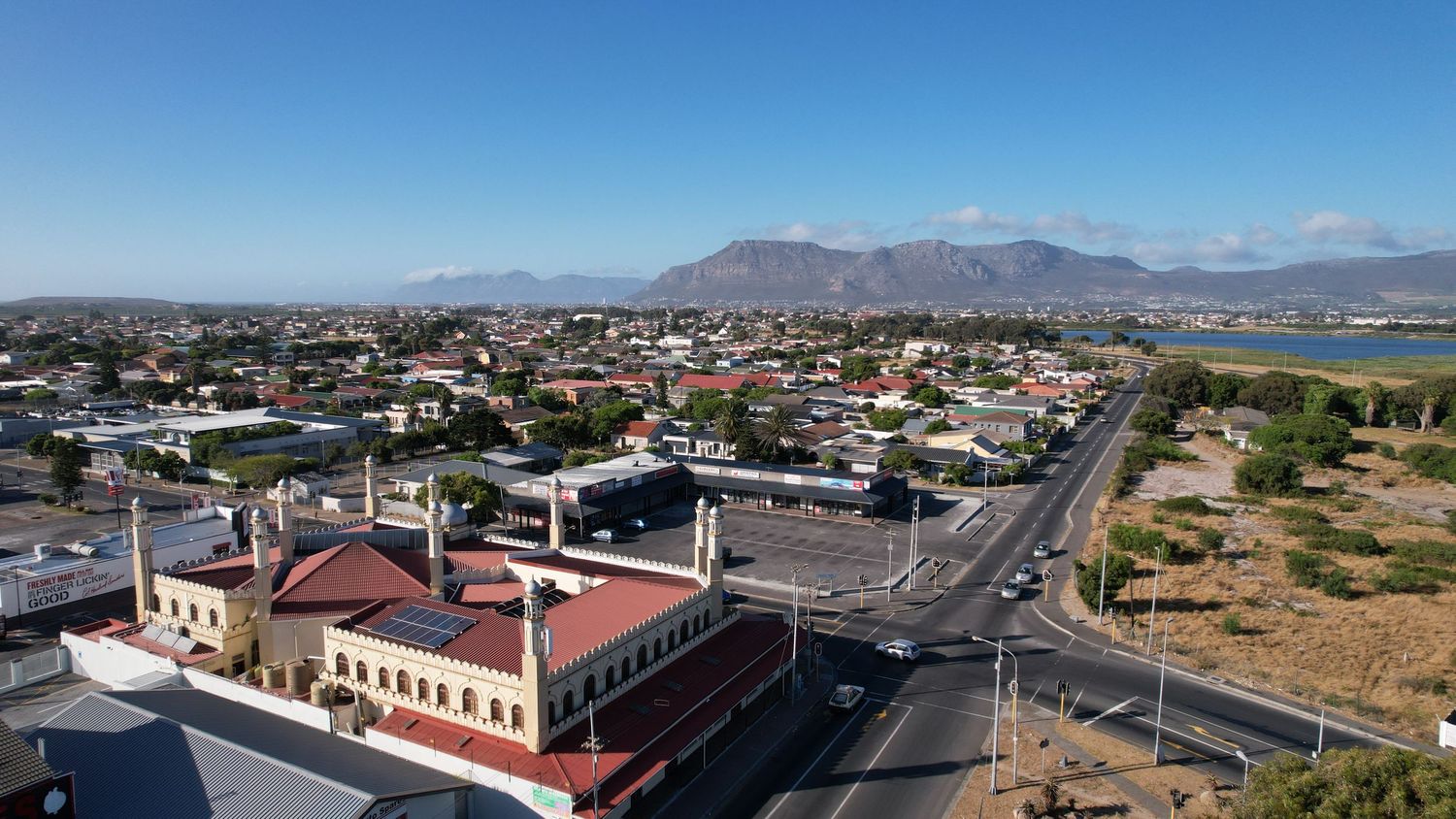 Aerial cityscape showing streets and buildings with mountain ranges visible in the distance.