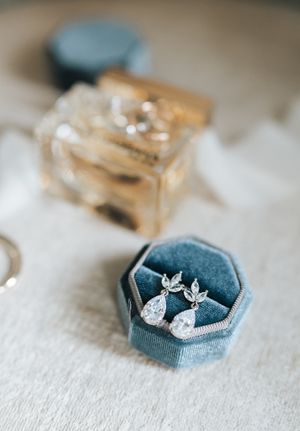 Elegant pear-shaped diamond drop earrings displayed in a blue velvet octagonal jewelry box.