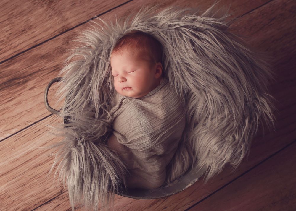 A peaceful newborn baby boy wrapped in soft fabrics, captured in a serene and intimate setting, showcasing the delicate beauty of early life