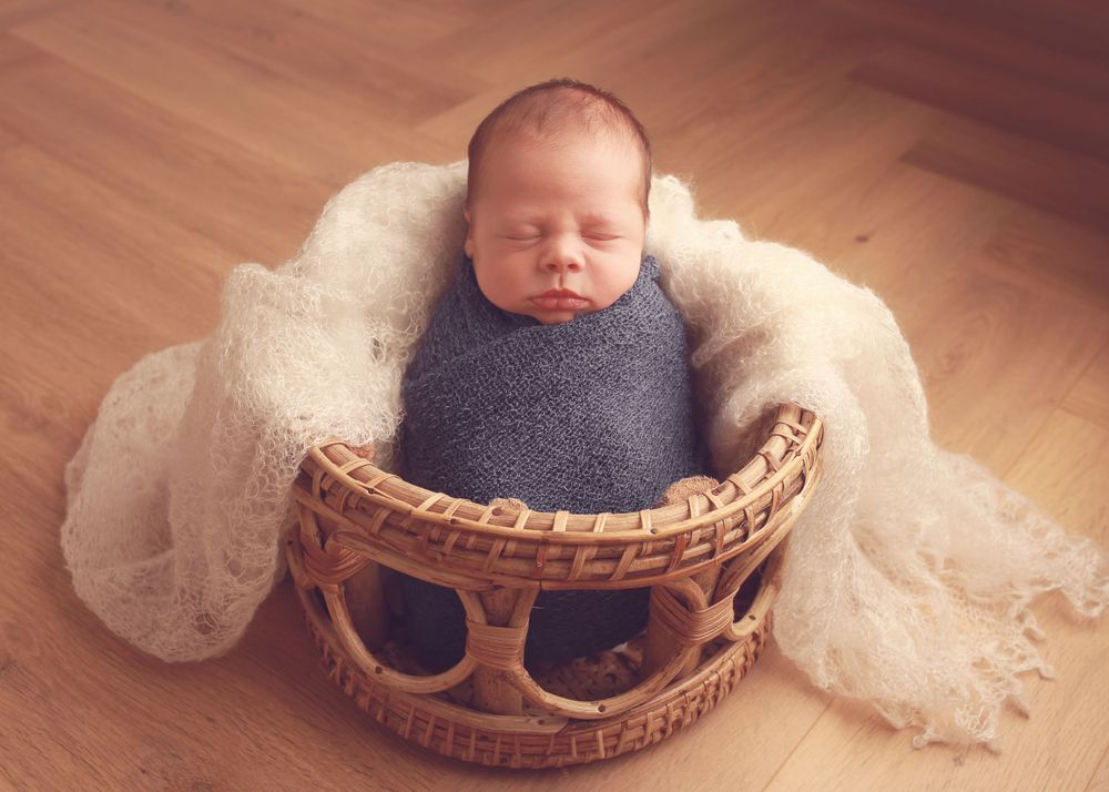 A peaceful newborn baby boy wrapped in soft fabrics, captured in a serene and intimate setting, showcasing the delicate beauty of early life