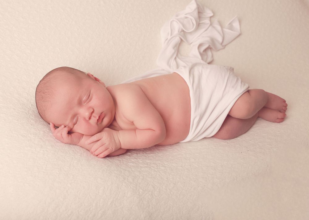 A peaceful newborn baby boy wrapped in soft fabrics, captured in a serene and intimate setting, showcasing the delicate beauty of early life