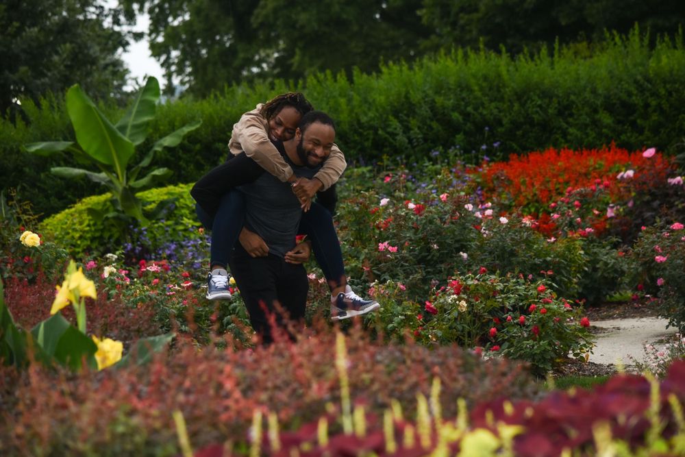 Couple embracing in colorful garden filled with blooming flowers.