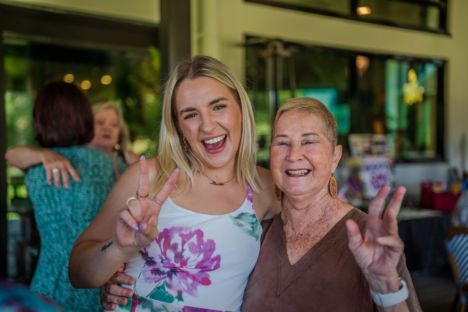 Two people sharing a joyful moment together while making peace signs at a restaurant.
