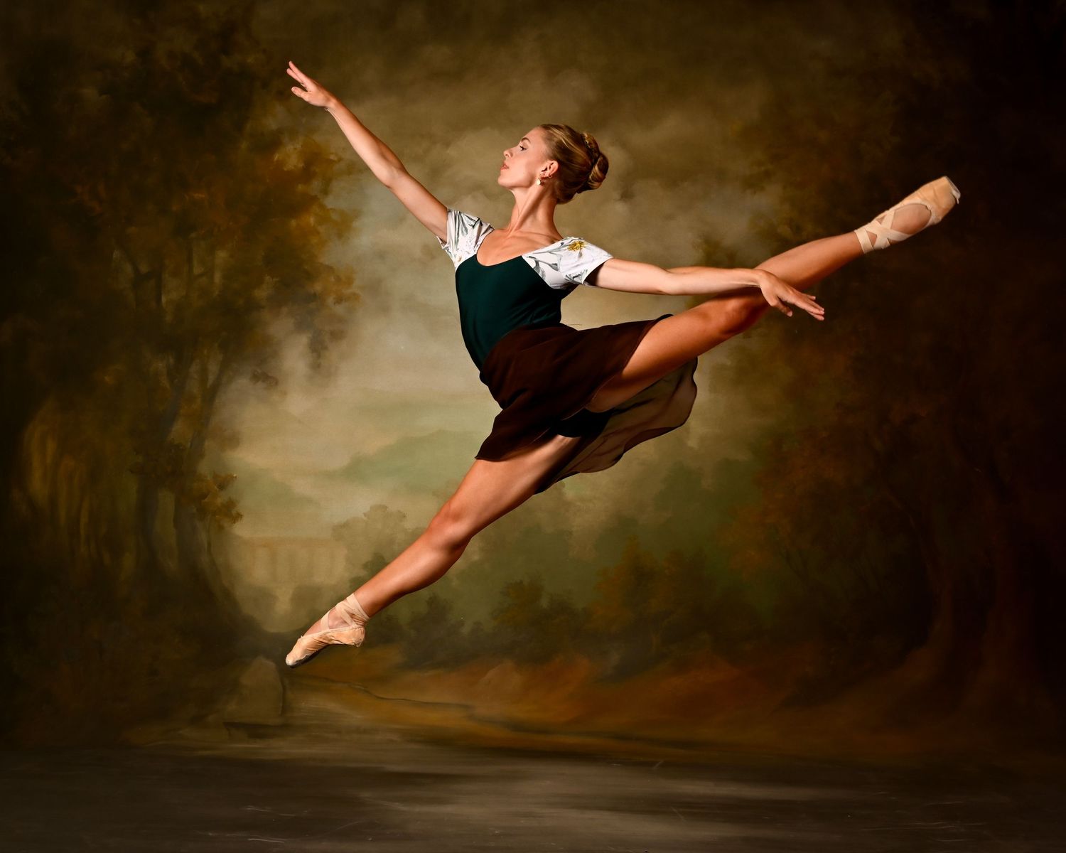 A ballerina performs a dramatic leap in a dark green dress against a moody brown backdrop.