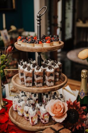 Three-tiered dessert stand with chocolate parfaits and fresh berries at a wedding reception.
