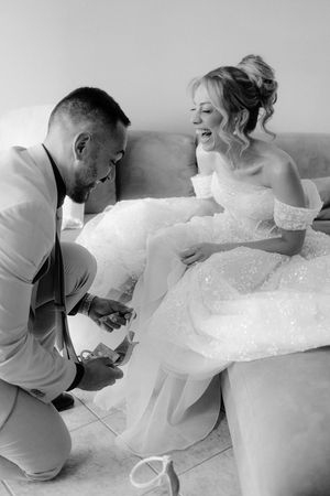 Black and white sequence showing a person helping adjust a bride's wedding dress on the floor.