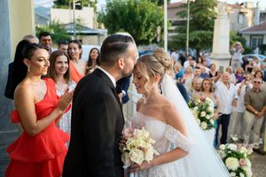 Wedding guests celebrate and dance during an outdoor reception on a sunny day.