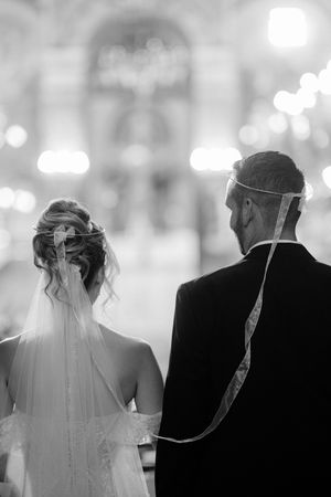 Black and white silhouette of wedding couple walking down aisle during ceremony.
