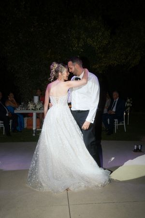 A couple shares a romantic dip dance move during their wedding reception on an illuminated dance floor.