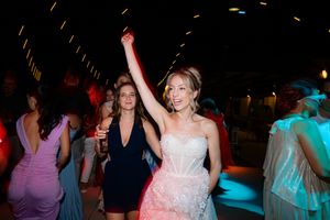 People dancing and celebrating at a wedding reception with colorful lighting and festive atmosphere.