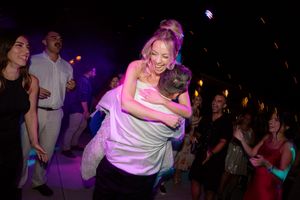 People dancing and socializing at a nightclub with purple lighting and a lively party atmosphere.