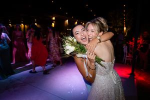 Wedding reception dance floor scene with guests celebrating under atmospheric lighting.