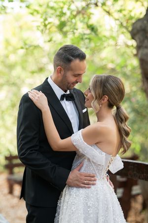 A romantic wedding couple shares an intimate dance moment in an outdoor garden setting with soft natural lighting.