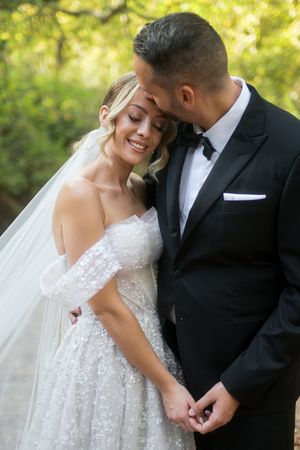A romantic wedding couple shares intimate moments in a series of outdoor portraits with natural lighting and greenery.