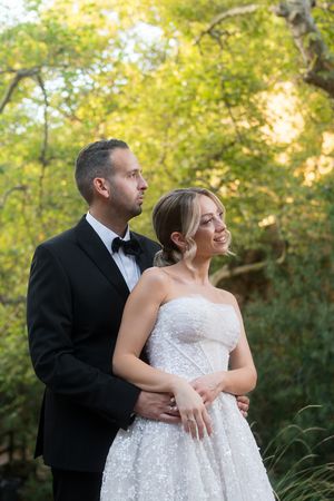 A couple in formal attire shares intimate moments against a backdrop of autumn trees.