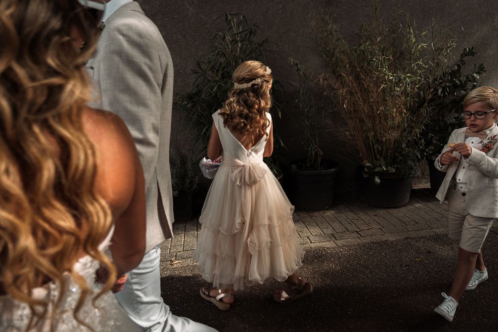 A small figure in a flowing tulle dress twirls on a stone patio during an elegant outdoor gathering.