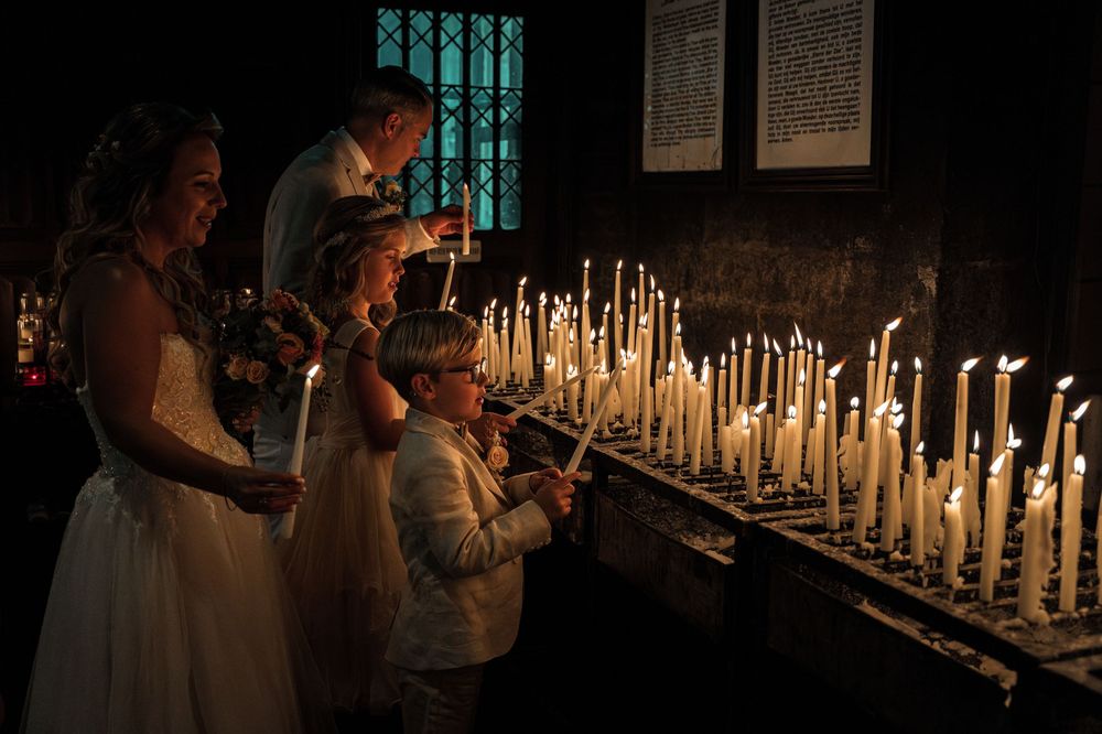 People lighting candles in a dark church during a religious ceremony, creating a warm and intimate atmosphere.