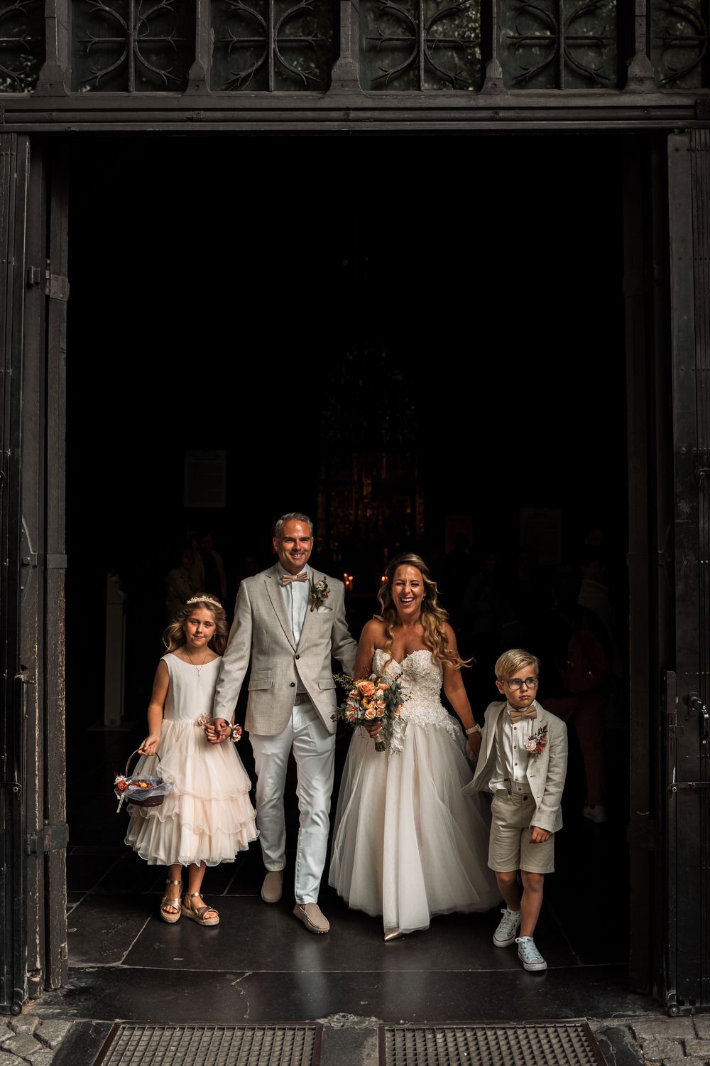 A wedding party poses in a series of artistic black and white frames showing different moments in a dark doorway.