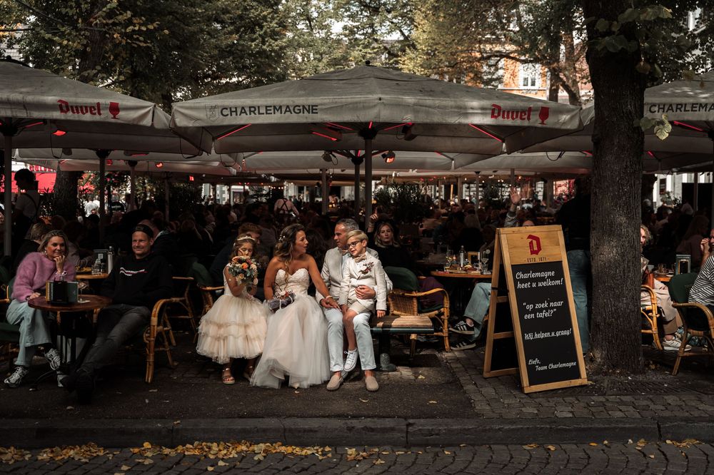 Diners enjoy an evening meal at an outdoor restaurant patio with umbrellas and chalkboard menu.