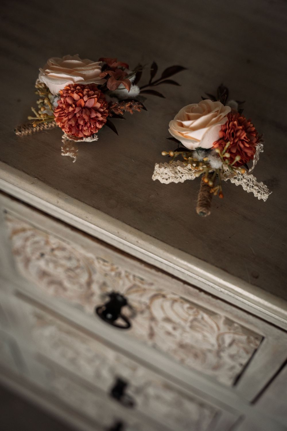 A series of vintage-style floral arrangements with dried flowers rest on an ornate white wooden surface with decorative trim.