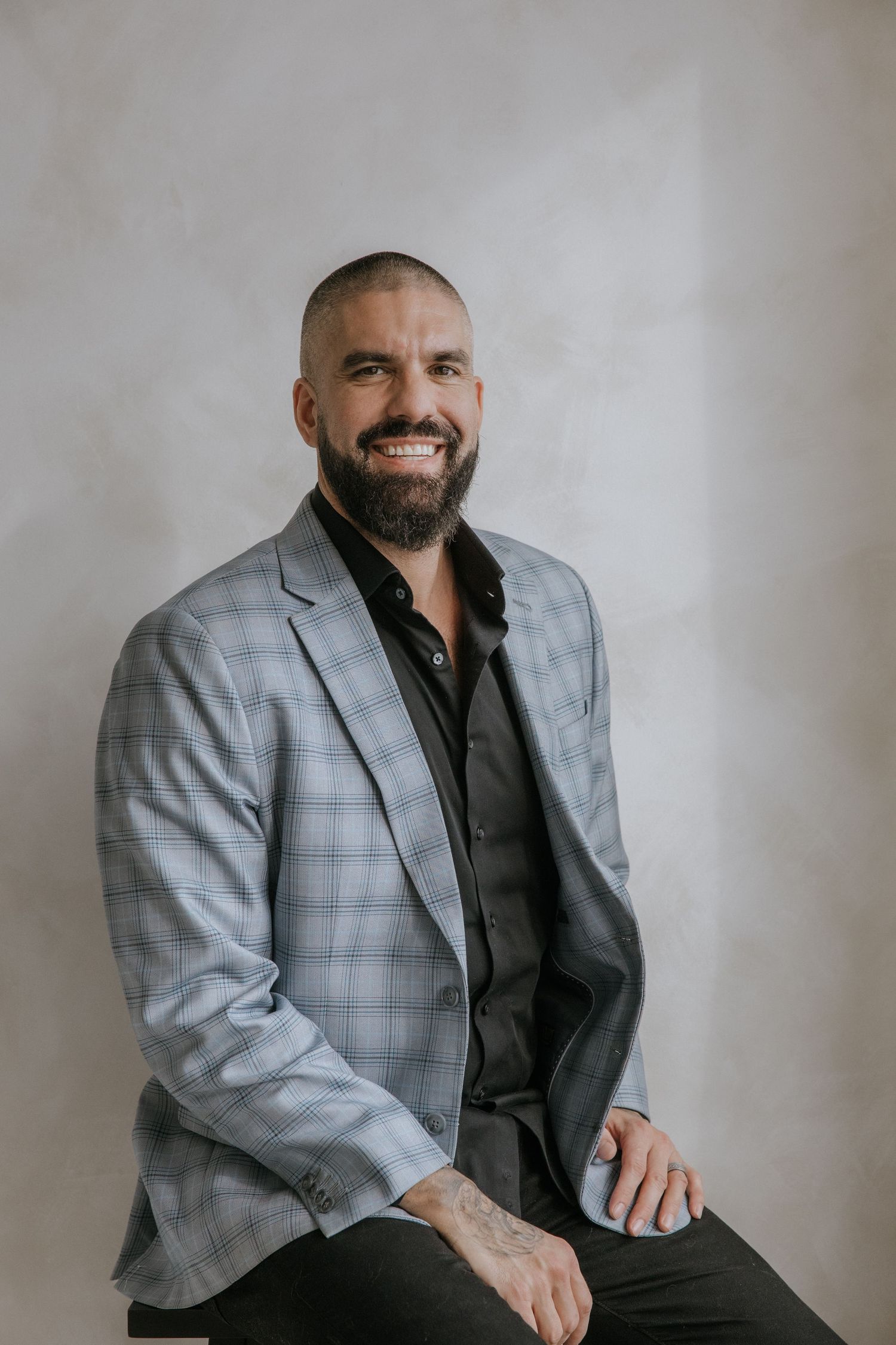 Professional studio portraits showing a person in a gray plaid blazer and black shirt against neutral background.