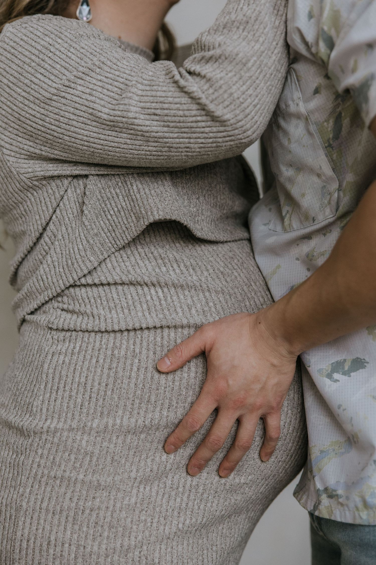 Close-up sequence showing hands gently touching and smoothing a textured gray knit fabric against a light background.