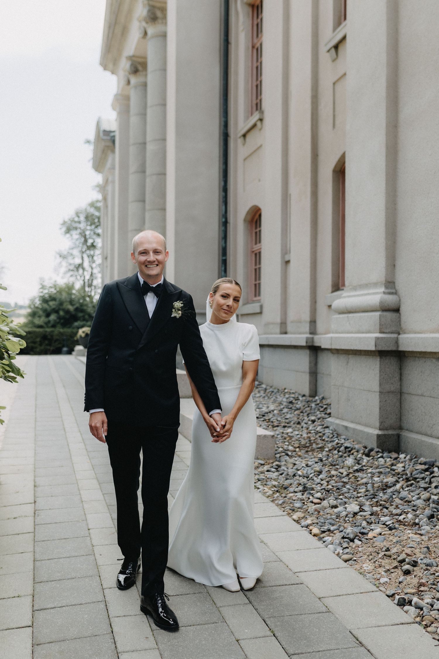 A series of four wedding photos showing a couple posing together against white columns with floral decorations.