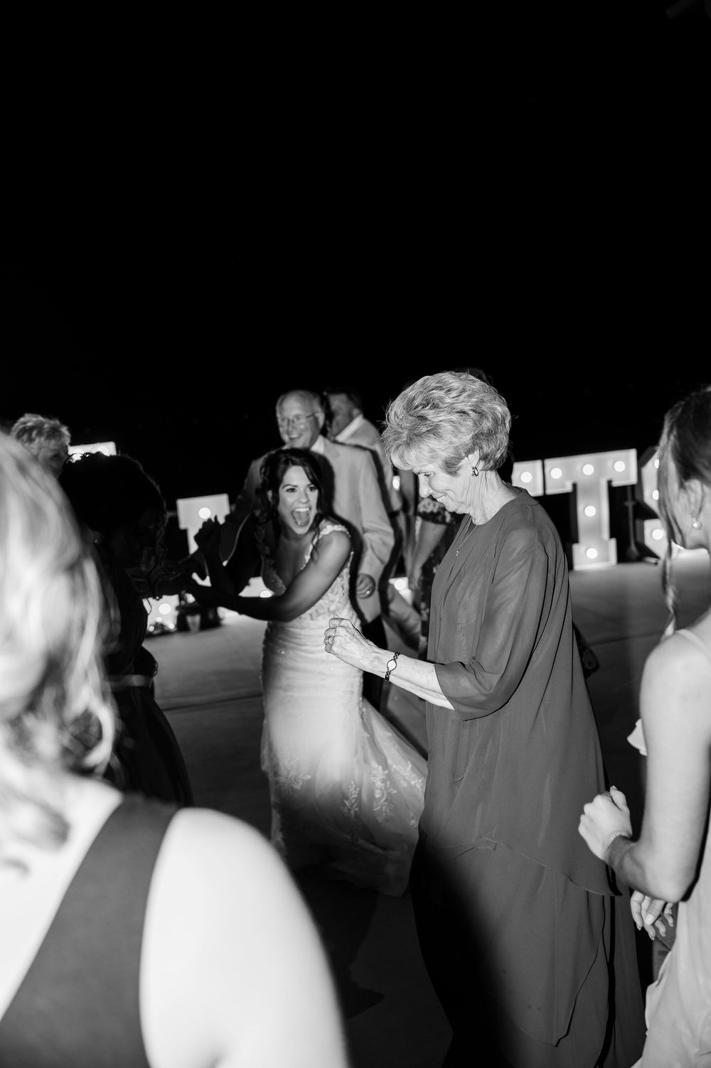 Black and white photo of wedding guests dancing and celebrating on the dance floor.