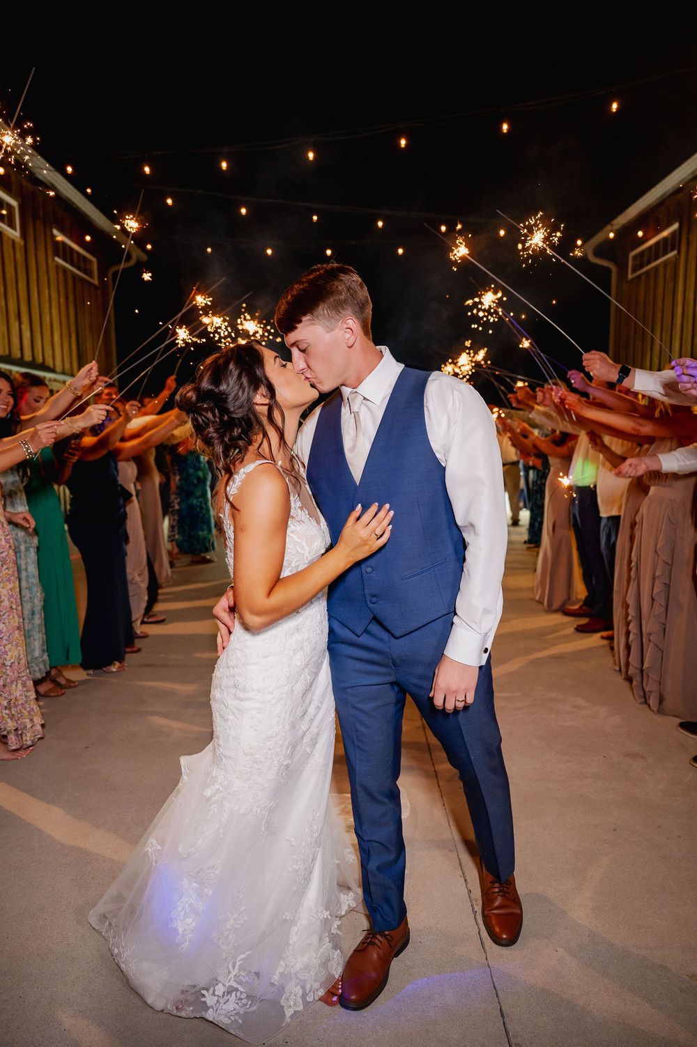 Couples dancing under string lights at an outdoor wedding reception venue.