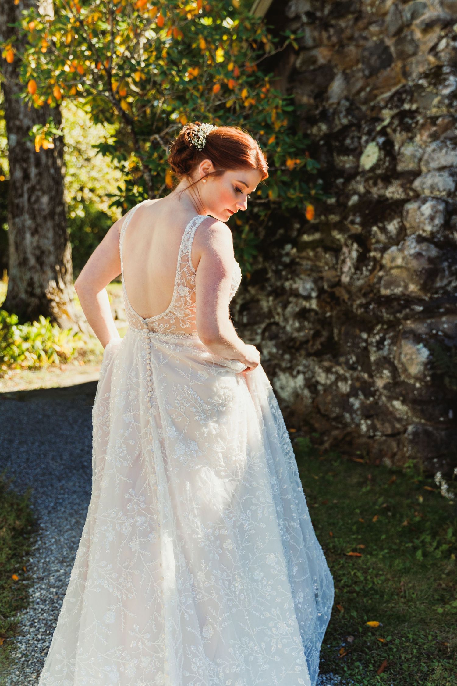 A bride in a lace wedding gown shows off the intricate back detail of her dress.