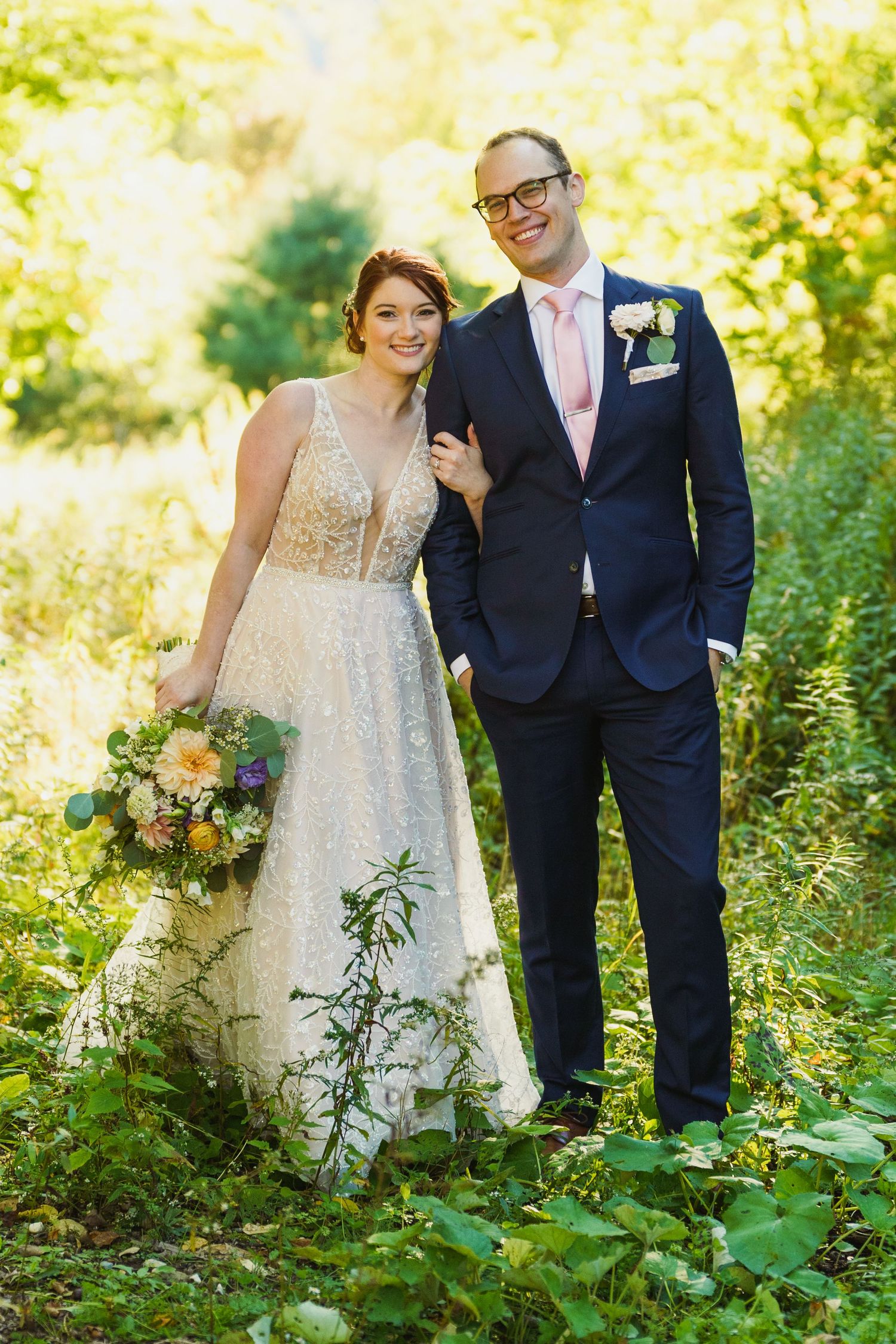 Romantic wedding portraits in a sunlit forest with couple in formal attire.