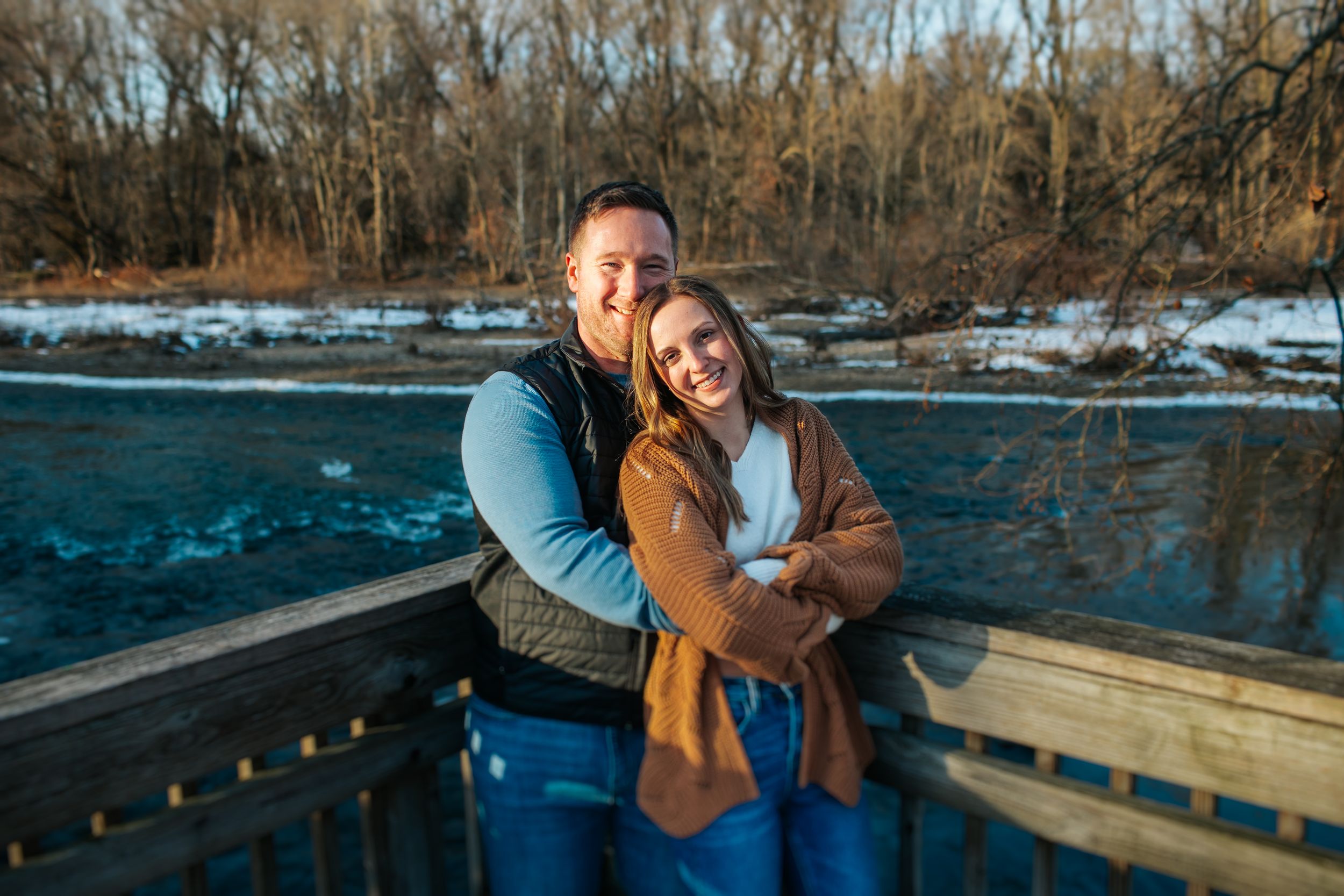 Two people share a romantic moment on a wooden bridge during winter.