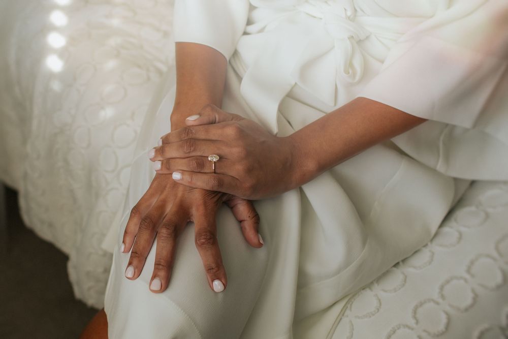 Close-up view of hands holding a white wedding dress fabric with delicate details and lace embellishments.