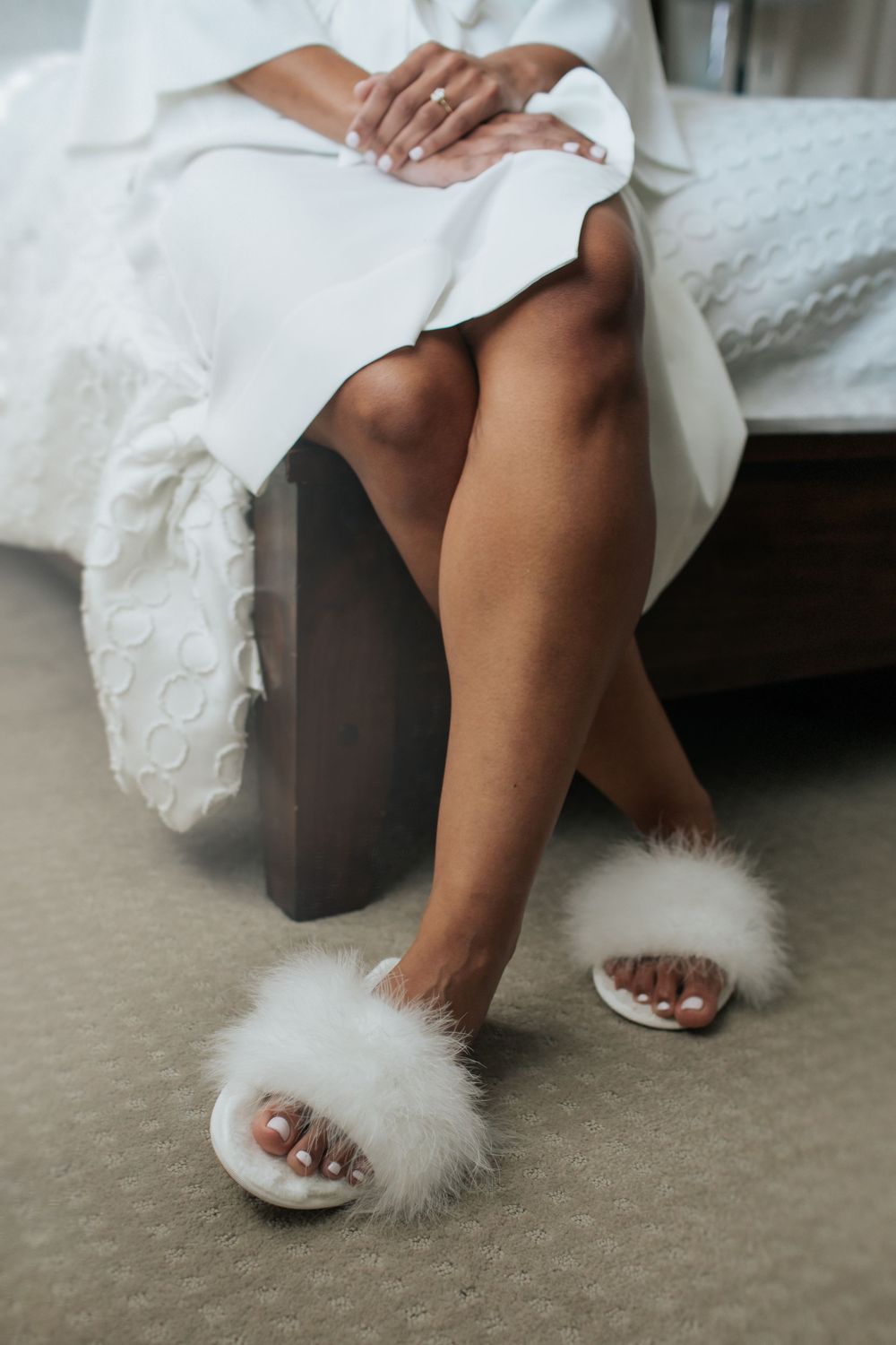 Feet wearing fluffy white bridal slippers shown in a series of close-up photos on beige carpet.