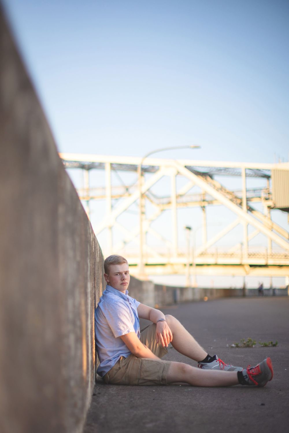 A person in a white shirt and shorts relaxes against a concrete wall during golden hour.
