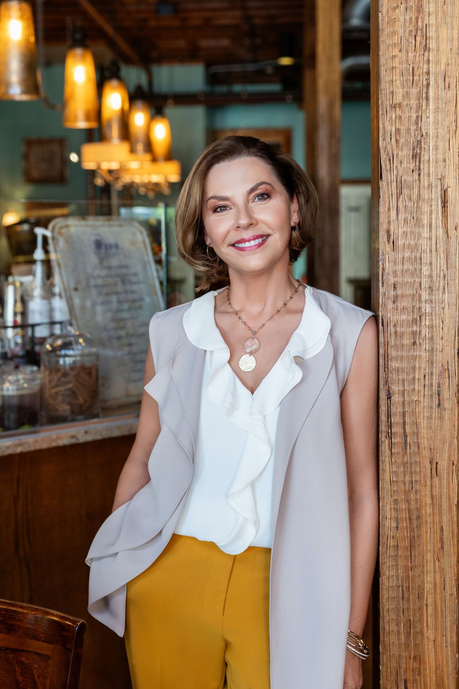 Professional portrait in a rustic restaurant setting with warm lighting and wooden beams.