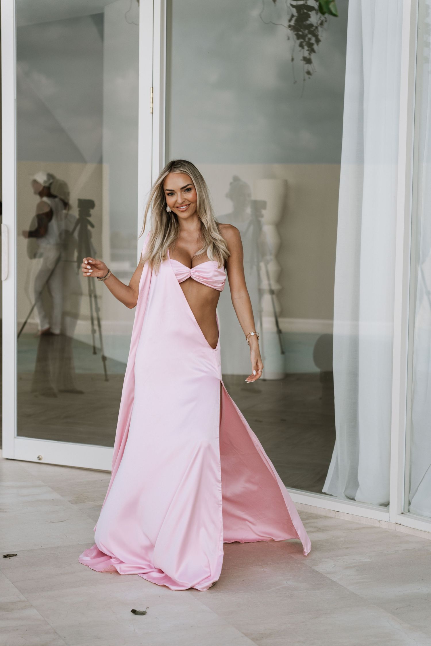 A series of photos showing someone in a flowing pink gown moving gracefully through a bright white interior space.