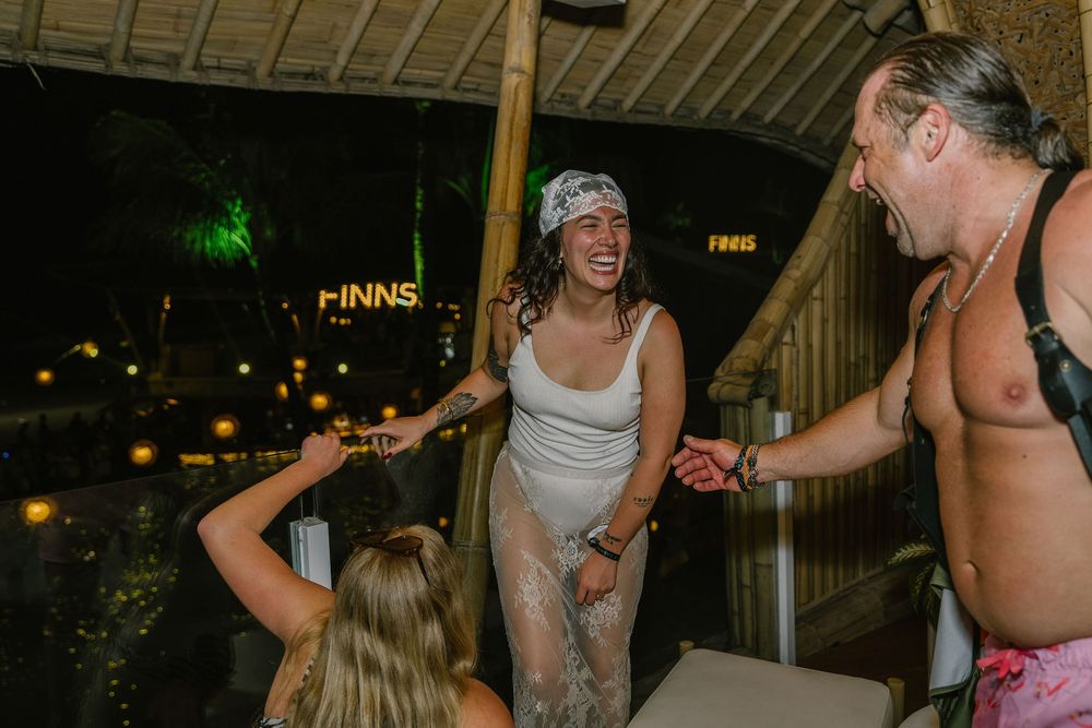 People laughing and celebrating at Finns venue at night, with a woman in a wet white dress enjoying a lively party.