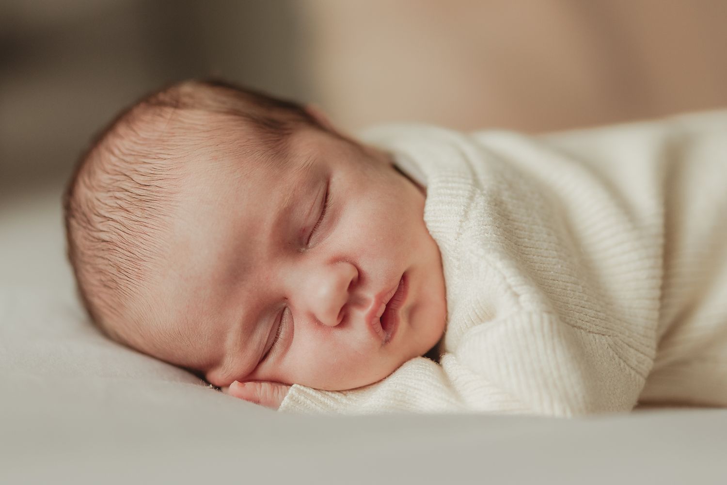 A series of peaceful sleeping baby photos in soft cream tones showing different angles of peaceful slumber.