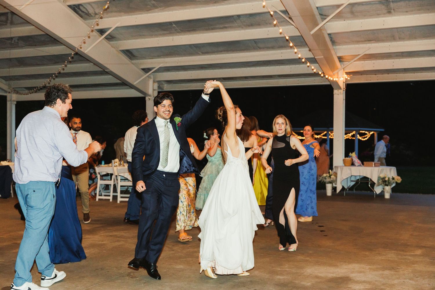 Wedding guests dancing and celebrating at an indoor reception venue.