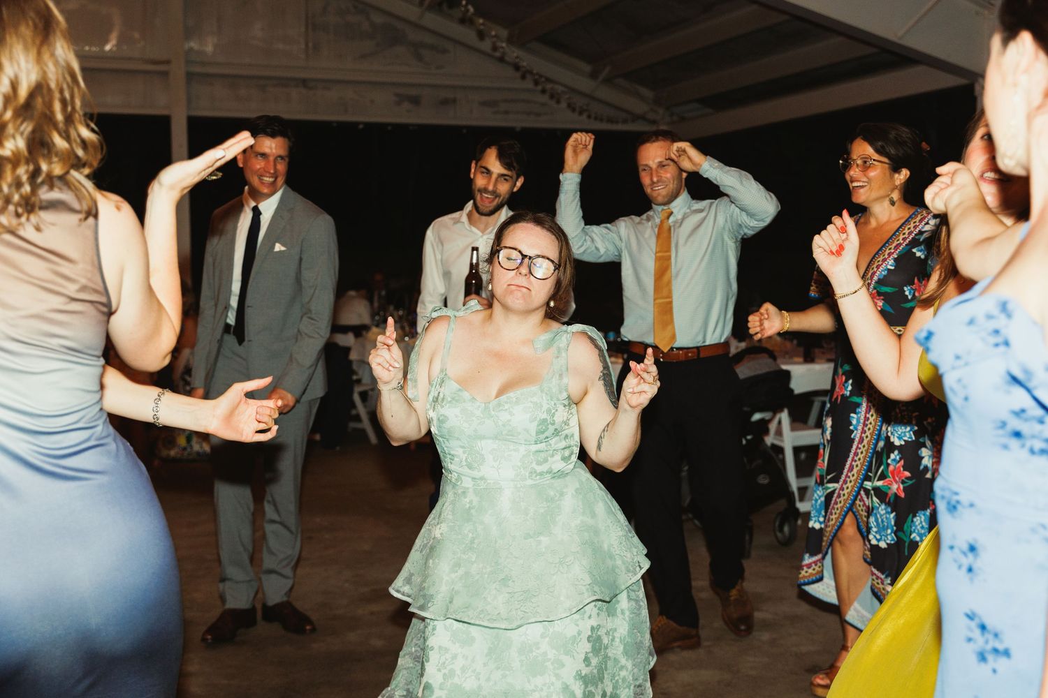 Wedding party and guests enjoying lively dance celebration at reception.