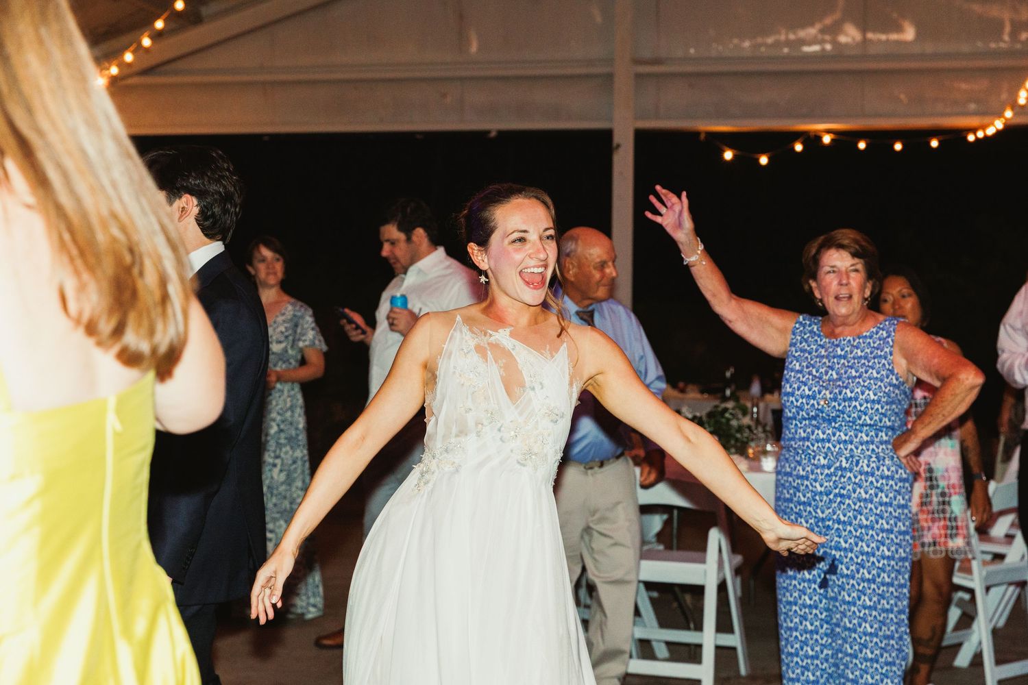Wedding guests dance and celebrate on a festively lit dance floor during an evening reception.