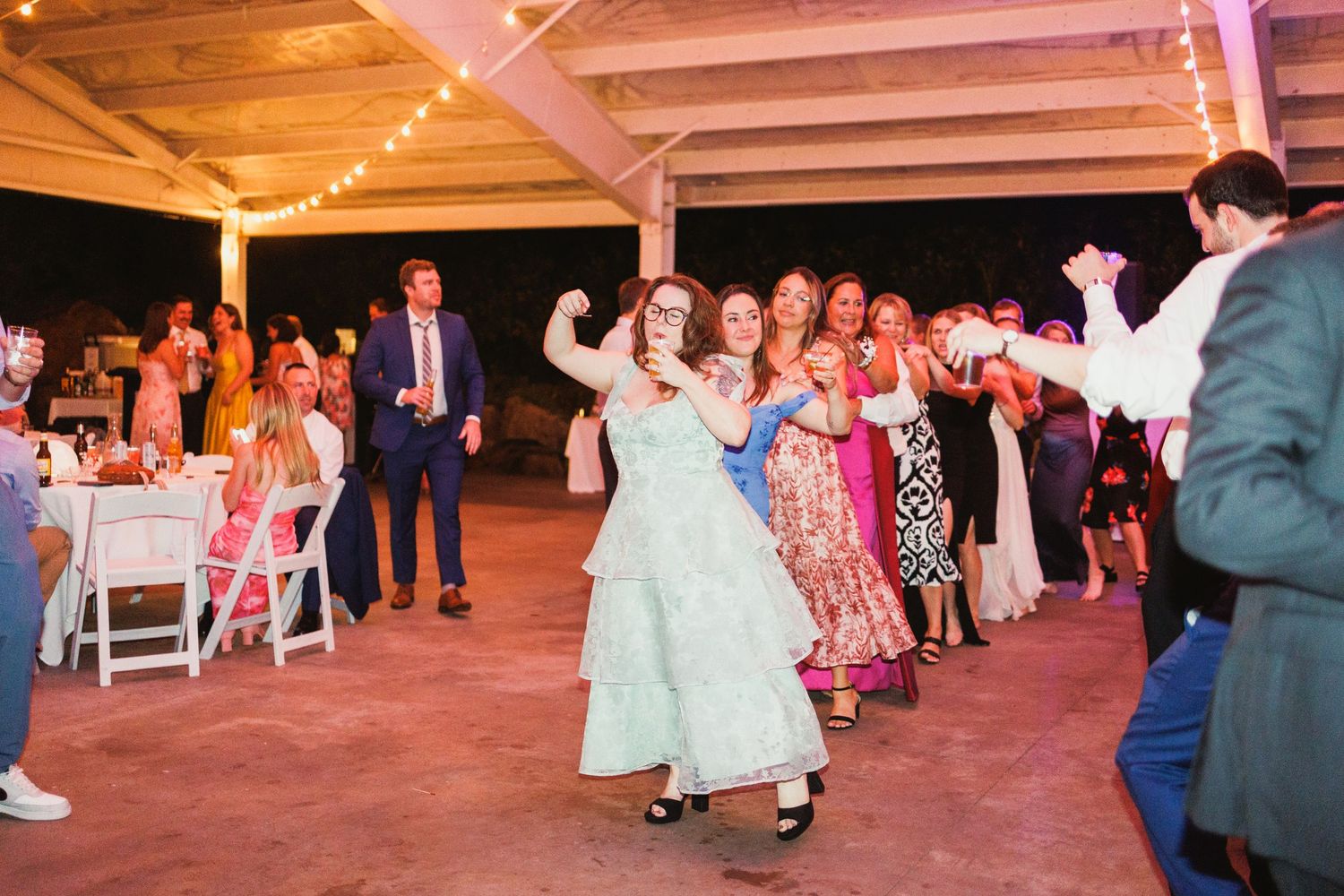 Wide shot of wedding reception venue with guests dancing and celebrating.