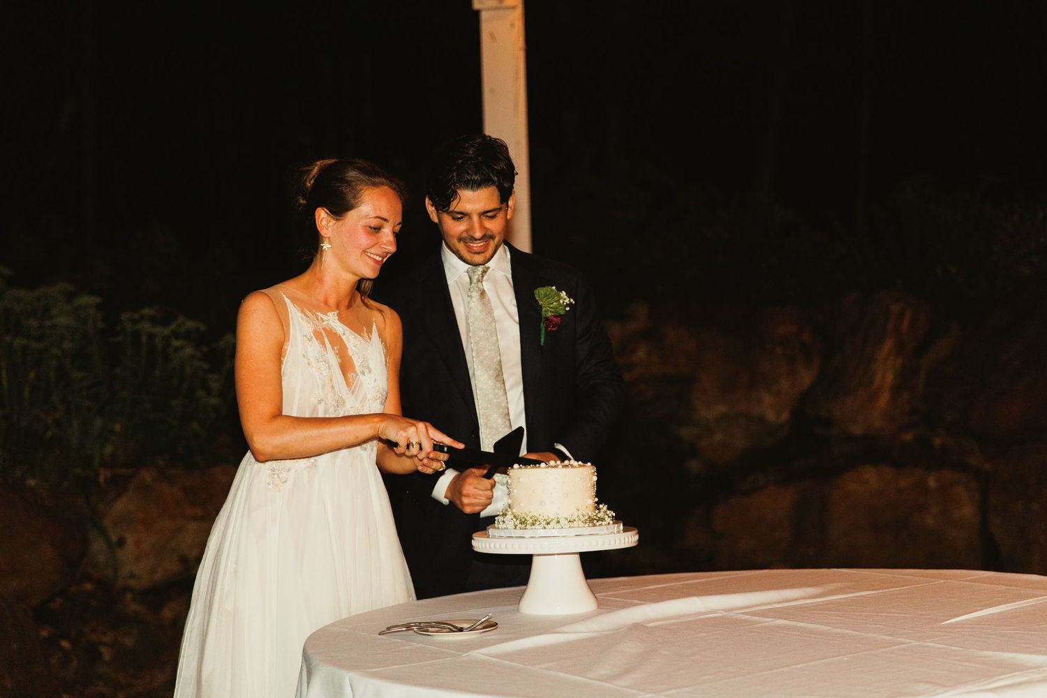 Couple cuts their wedding cake together during evening reception.