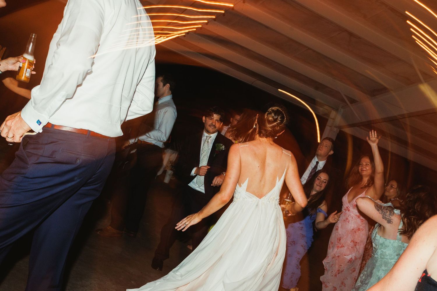 Wedding reception dance floor filled with guests celebrating under warm lighting.